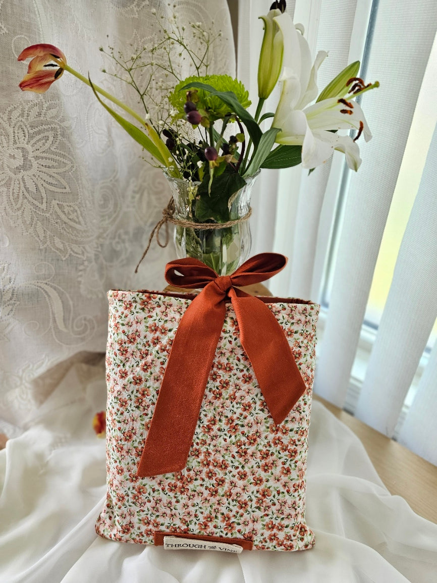 Coral florals on ivory fabric, rust fabric ribbon tie, quilted bible sleeve. Floral arrangement in background.