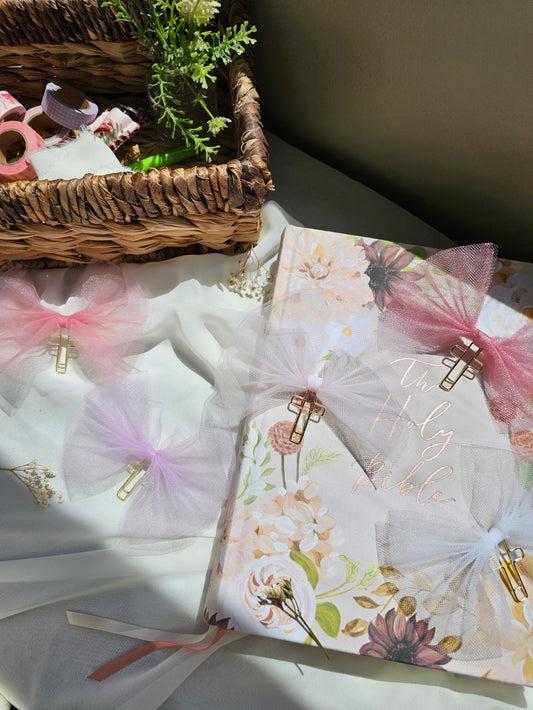 Tulle bow bookmarks on an open book with a candle and basket in the background.