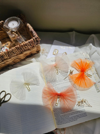 Tulle bow bookmarks on an open book with a candle and basket in the background.