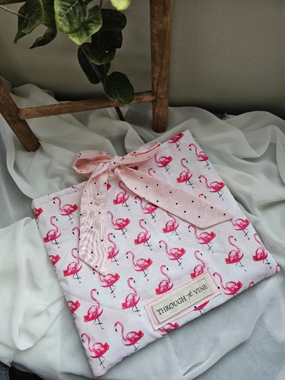Flamingos on light pink fabric ribbon tie, quilted bible sleeve. Wooden ladder in background. 