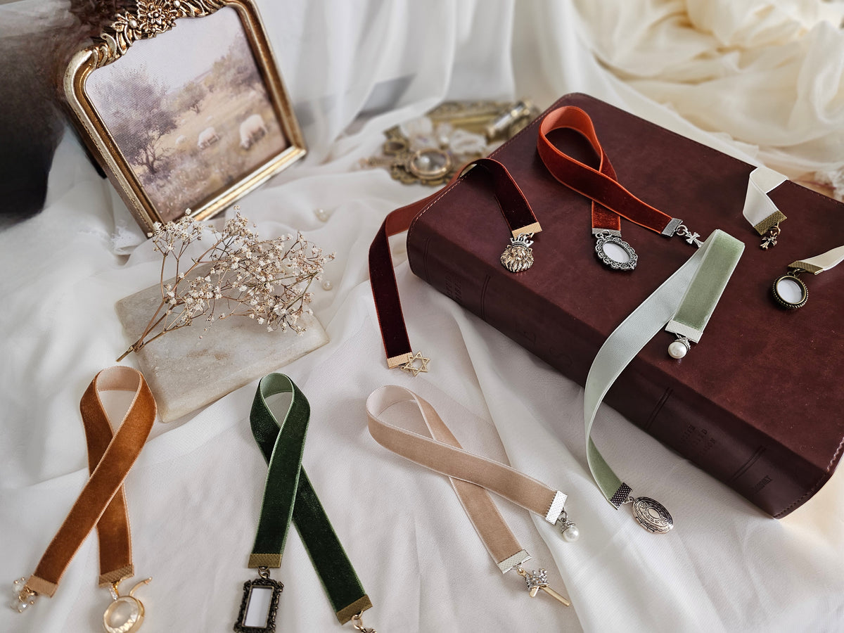 Ribbons with charms on white backdrop surrounded by bible and props. 