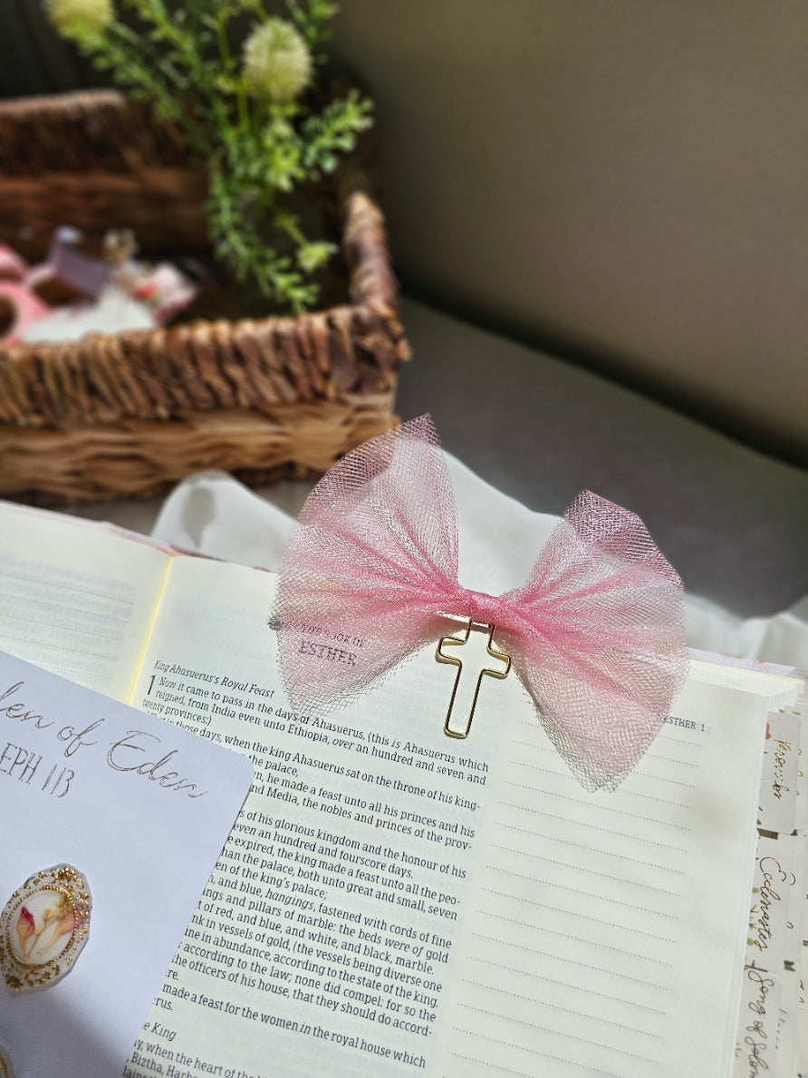 Shimmery Pink Tulle bookmark bow including a cross on an open book with a plant beside it and other stationery.