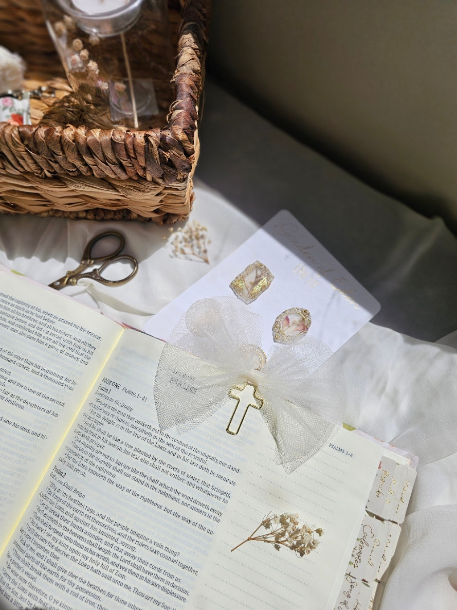 Cream Tulle bookmark bow including a cross on an open book with a plant beside it and other stationery.