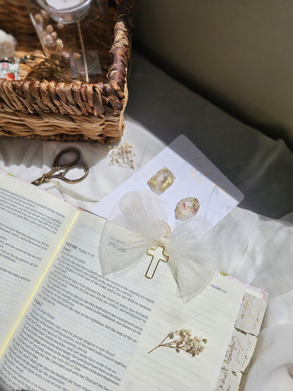 Cream Tulle bookmark bow including a cross on an open book with a plant beside it and other stationery.