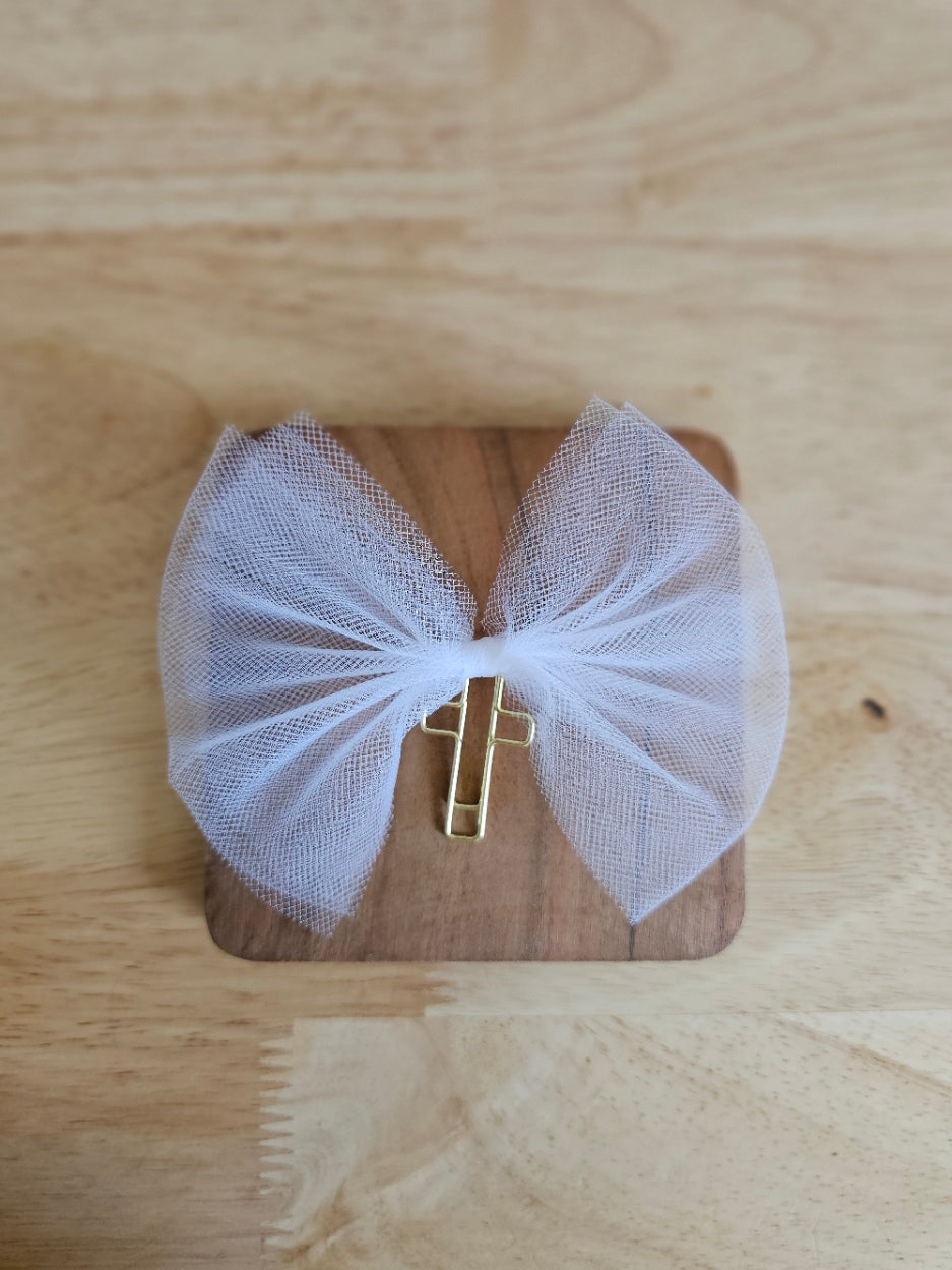 White tulle bow with a gold cross on a wooden box against a wooden background