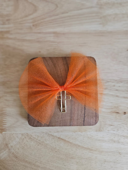 Bright Orange tulle bow with a gold cross on a wooden box against a wooden background