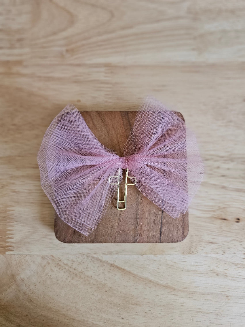 Matte pink tulle bow with a gold cross on a wooden box against a wooden background