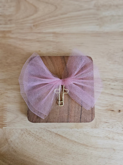 Matte pink tulle bow with a gold cross on a wooden box against a wooden background