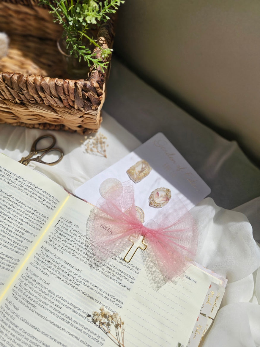 Matte Pink Tulle bookmark bow including a cross on an open book with a plant beside it and other stationery.