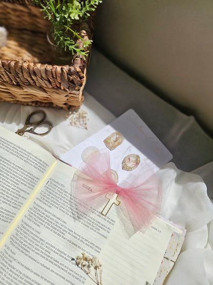 Matte Pink Tulle bookmark bow including a cross on an open book with a plant beside it and other stationery.