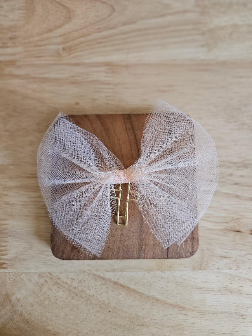 Light Orange tulle bow with a gold cross on a wooden box against a wooden background
