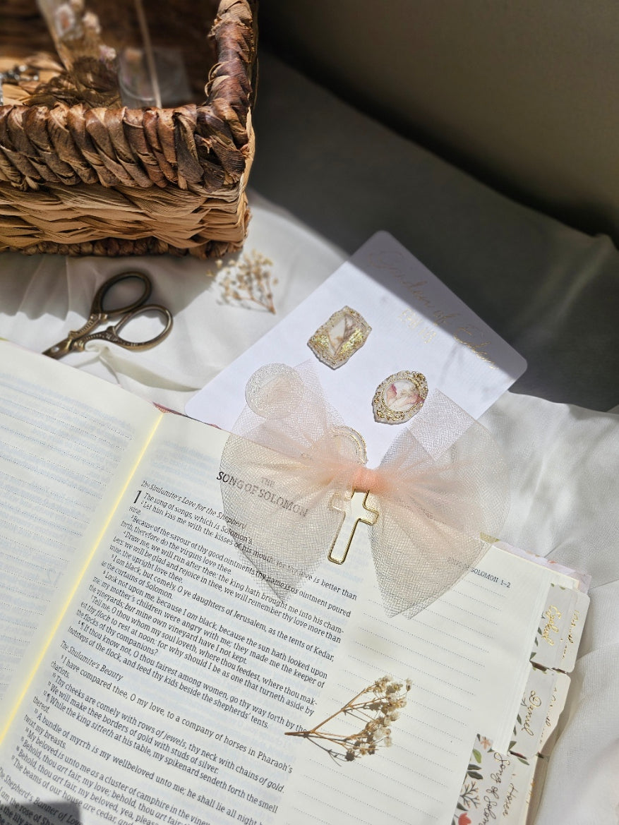 Light Orange Tulle bookmark bow including a cross on an open book with a plant beside it and other stationery.