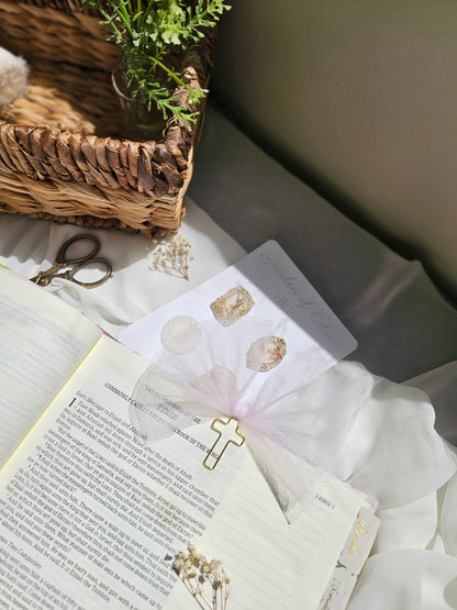 Light Pink Tulle bookmark bow including a cross on an open book with a plant beside it and other stationery.