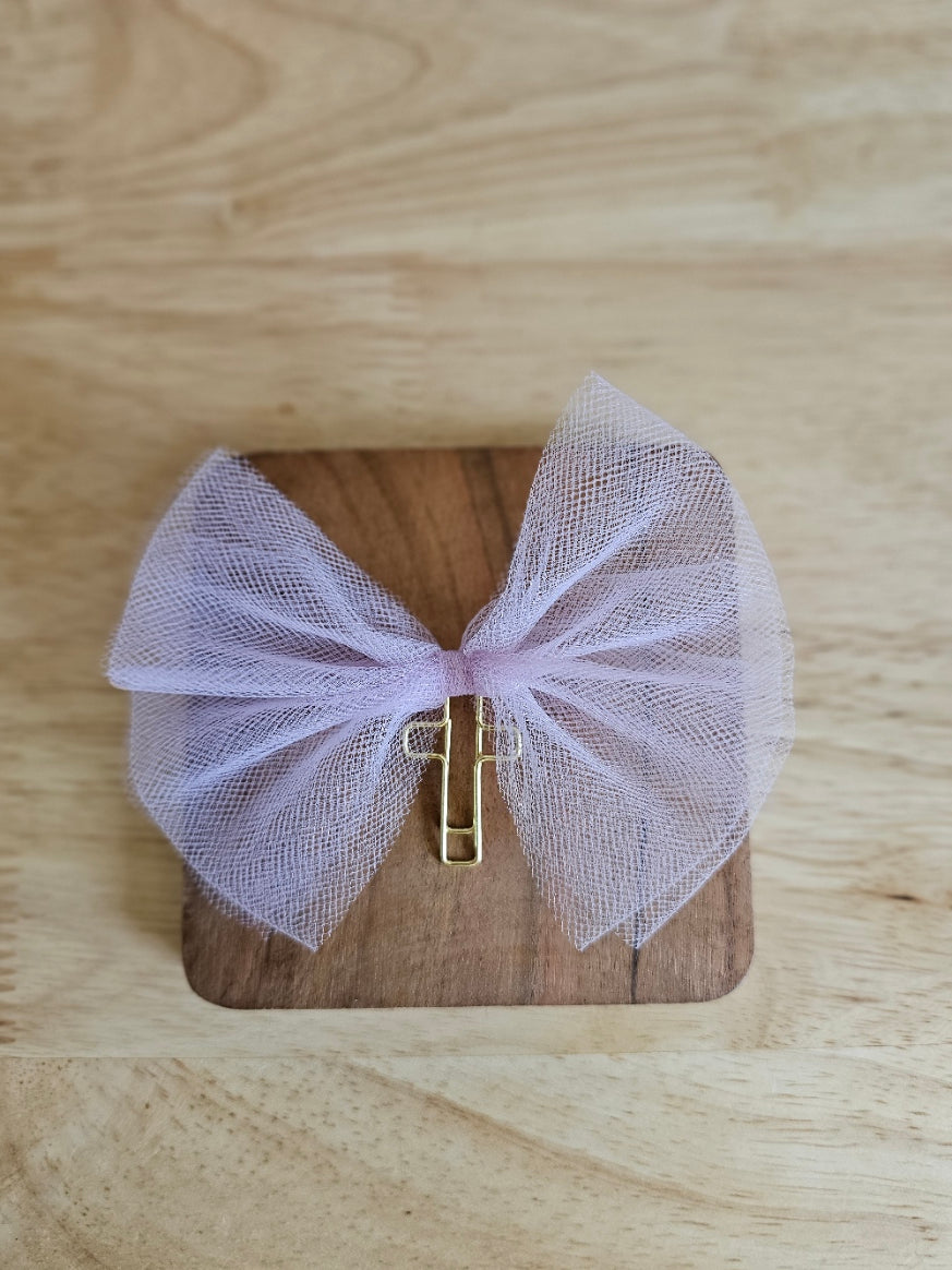 Purple tulle bow with a gold cross on a wooden box against a wooden background