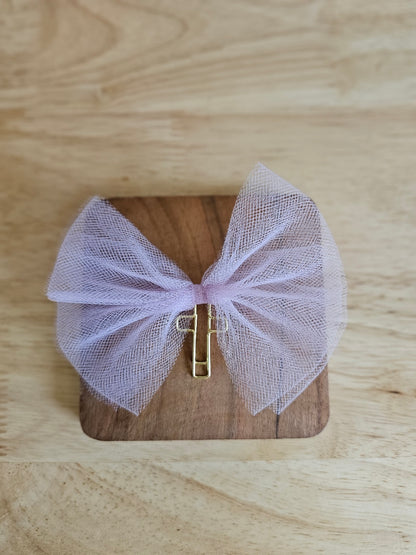 Purple tulle bow with a gold cross on a wooden box against a wooden background