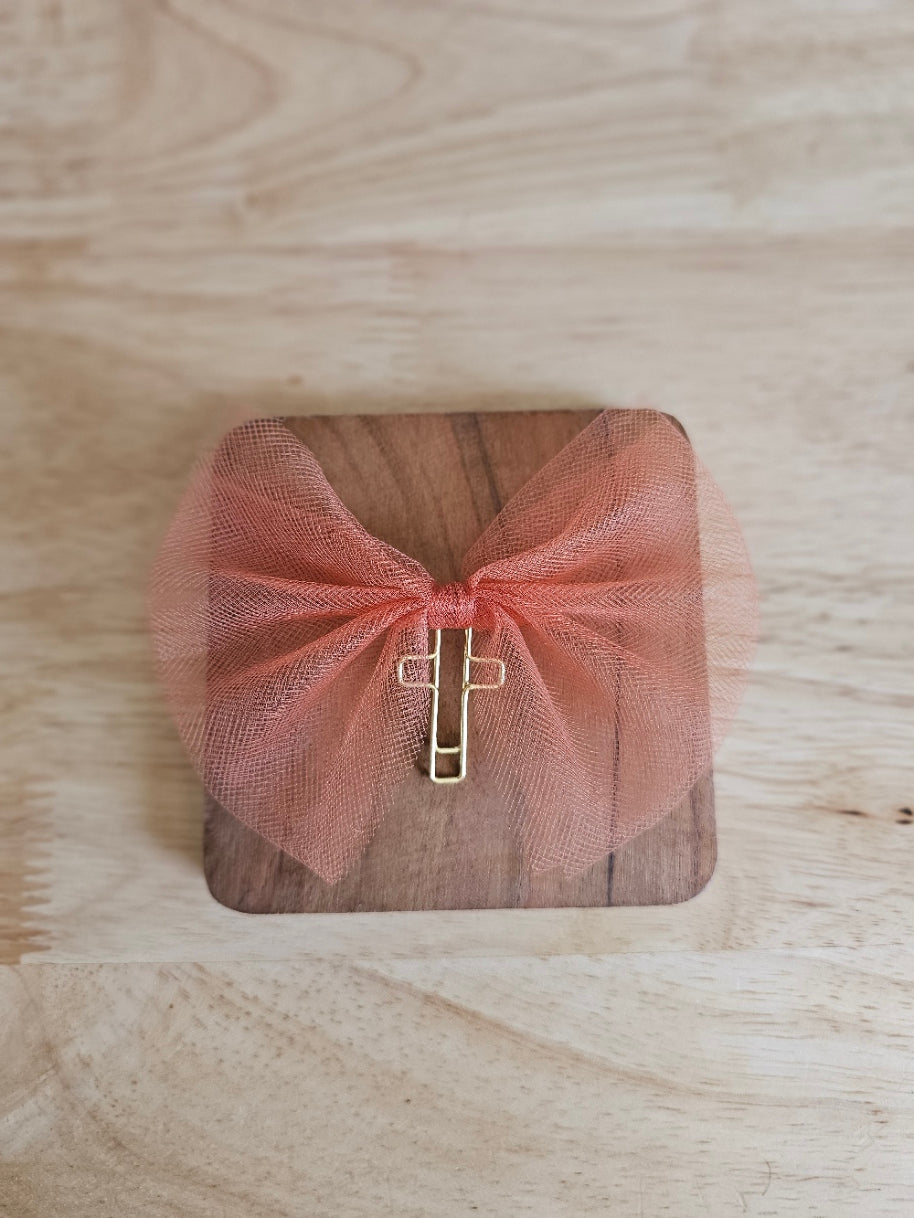 Dull Orange tulle bow with a gold cross on a wooden box against a wooden background