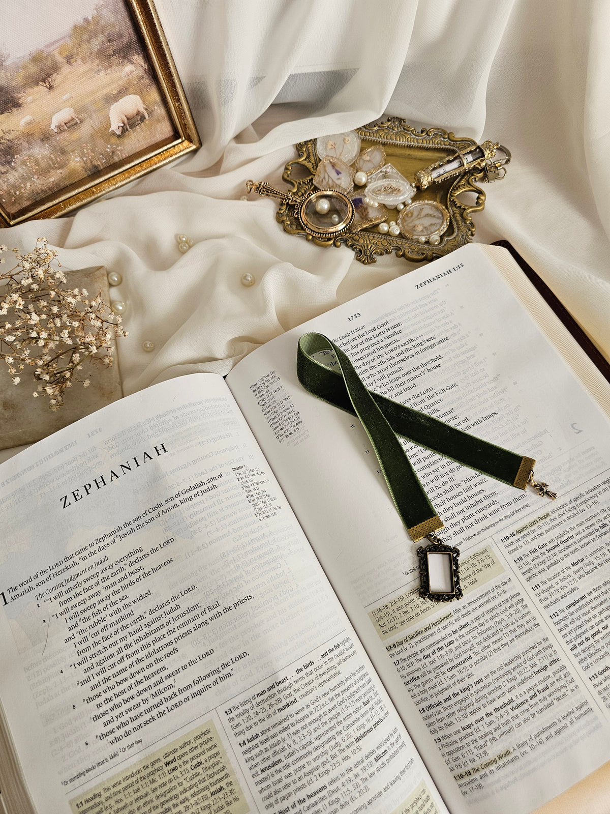 Dark green velvet ribbon with brass frame and cross charms on each end sitting on an open Bible.