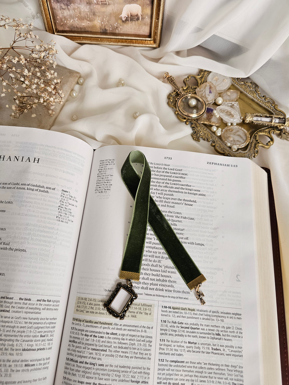 Dark green velvet ribbon with brass frame and cross charms on each end sitting on an open Bible.