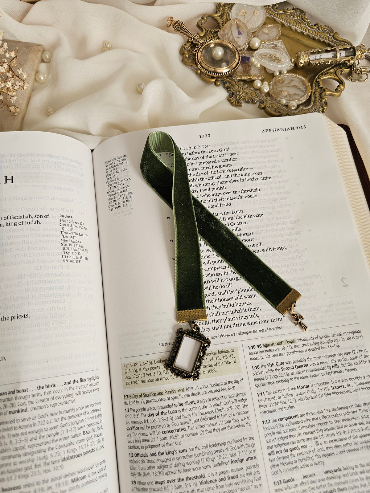 Dark green velvet ribbon with brass frame and cross charms on each end sitting on an open Bible.